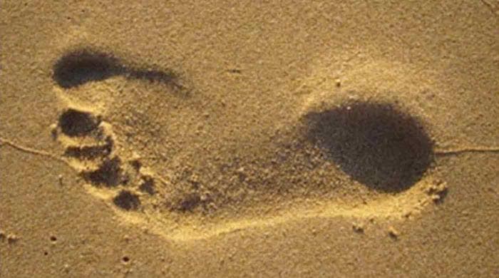 The footprint in the sand appears concave